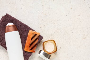 Beyaz grunge arka planda şampuanlı, taraklı ve saç maskeli bir havlu.