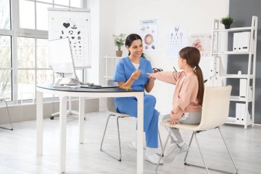 Klinikte göz doktoruyla gözlük seçen küçük bir kız.