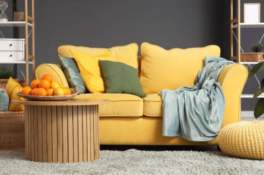 Süslü oturma odasındaki kanepenin yanındaki sehpanın üzerinde narenciye tabağı var.