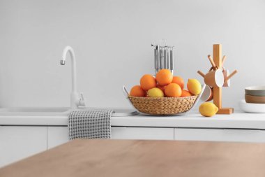 Beyaz stil mutfaktaki tezgahta turuncularla dolu bir sepet.