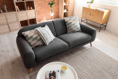 Oturma odasının içinde siyah kanepe ve çekmeceler.