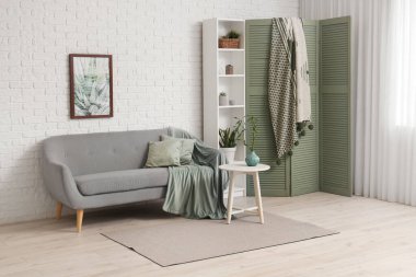 Konforlu kanepesi, raf ünitesi ve katlanır ekranı olan modern oturma odası.