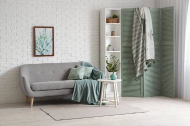 Konforlu kanepesi, raf ünitesi ve katlanır ekranı olan modern oturma odası.