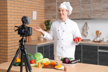 Taze sebzeli erkek şef mutfakta yemek pişirme videosu kaydediyor.