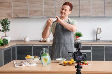 Genç adam onun mutfakta ev yapımı limonata yaptığını videoya kaydediyor.