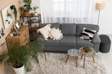 Siyah kanepesi, sehpası, çiçekleri ve tahtasıyla şık bir oturma odası.