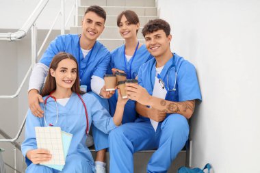 Üniversitede merdivenlerde kahve içen bir grup tıp öğrencisi.