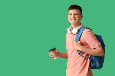 Sırt çantası ve yeşil arka planda bir fincan kahvesi olan genç çocuk.