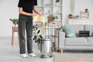 Evdeki çöp kutusunun yanında çöp torbası yırtan kadın.