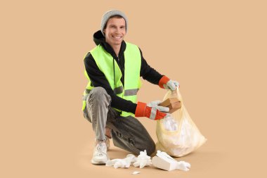 Erkek leş yiyiciler bej arka planda çöp torbalarına atıyorlar.