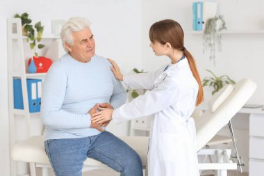 Kadın doktor klinikte hasta ve olgun bir adamla çalışıyor.