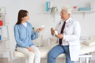 Erkek doktor klinikteki kadın hastaya ilaç veriyor.