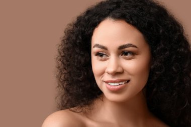 Kahverengi arka planda sağlıklı bir teni olan güzel, mutlu, Afro-Amerikalı bir kadın.