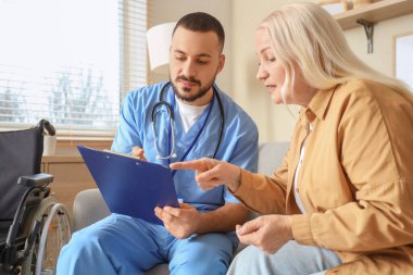 Erkek doktor evde olgun bir kadınla çalışıyor.