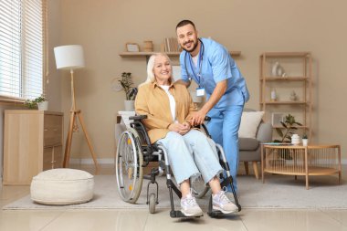 Evde tekerlekli sandalyede yetişkin bir kadınla erkek doktor.