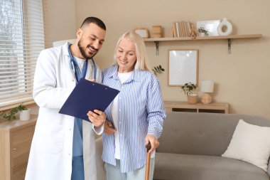 Erkek doktor evde olgun bir kadınla çalışıyor.