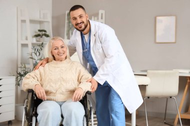 Hastanede tekerlekli sandalyede yetişkin bir kadınla erkek doktor.