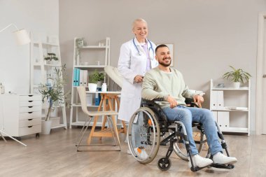 Kadın doktor ve tekerlekli sandalyedeki genç adam hastanede.