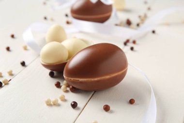 Beyaz ahşap arka planda tatlı çikolata yumurtaları ve dağınık şekerler.