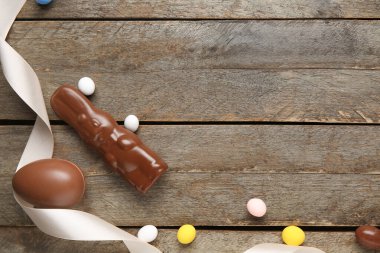 Paskalya tavşanlı tatlı çikolata yumurtası ve ahşap arka planda şekerler.