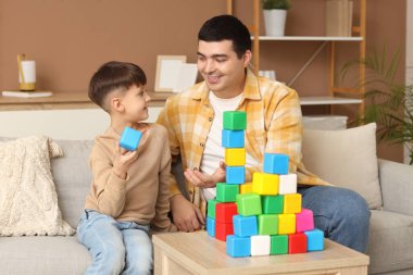 Küçük çocuk ve babası evde küplerle oynuyorlar.