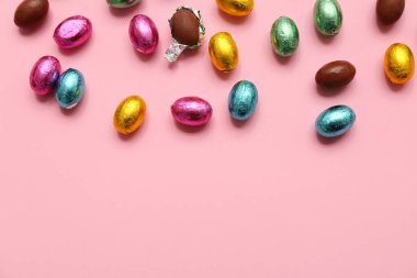 Paketlenmemiş ve paketlenmemiş paskalya yumurtaları pembe arka planda folyoda