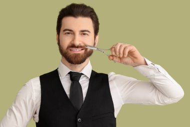 Yeşil arka planda makaslı sakallı genç bir adam.