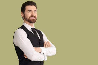 Yeşil arka planda çapraz kollu sakallı genç adam.