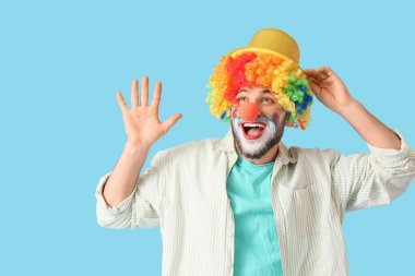 Mavi arka planda palyaço kılığına girmiş genç adam.