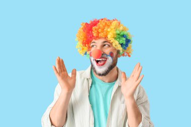 Mavi arka planda palyaço kılığına girmiş genç adam.