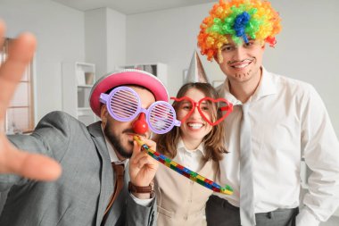 Komik kılık değiştirmiş genç iş arkadaşları ofiste selfie çekiyorlar. 1 Nisan Kutlaması