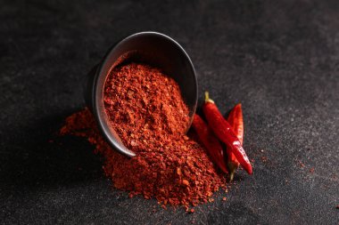 Siyah zemin üzerinde kırmızı biber tozu olan bir kase.