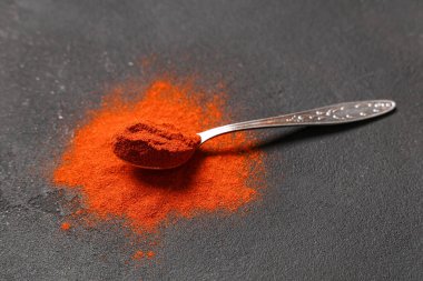 Siyah zemin üzerinde kırmızı biber tozu olan kaşık