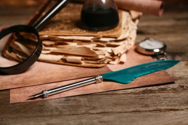 Ahşap arka planda kalem, büyüteç ve cep saati olan eski bir kitap.