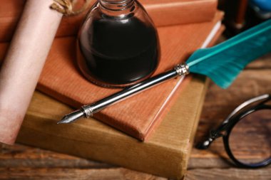 Kalemi, mürekkebi ve tahta arka planı olan eski kitaplar.