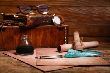 Ahşap zemin üzerinde kalem, mürekkep ve parşömen bulunan eski kağıt çarşaflar