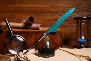 Ahşap zemin üzerinde kalem ve büyüteç olan eski bir kitap.