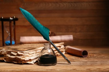 Kalemi, mürekkebi ve tahta arka planı olan eski bir kitap.