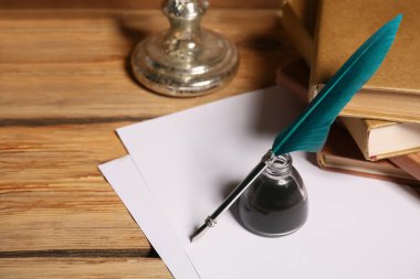 Ahşap arka planda kalem, mürekkep hokkası ve kağıt çarşaflı kitaplar