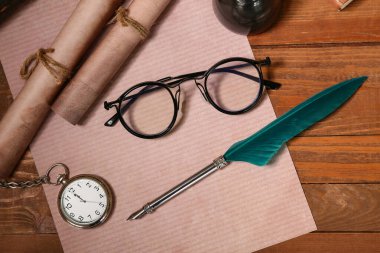 Ahşap zemin üzerinde kalem, parşömen, cep saati ve gözlüklü kağıt çarşaf