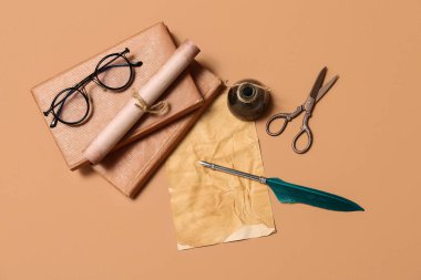 Bej arka planda kitap, tükenmez kalem, mürekkep hokkası, kaydırma ve makas bulunan eski kağıt sayfası