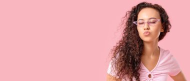 Güzel Afro-Amerikalı kadın pembe arka planda güneş gözlüğü takıyor.