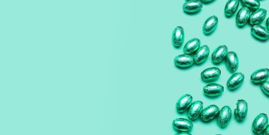 Turkuaz arka planda birçok çikolatalı Paskalya yumurtası. Metin ve üst görünüm için alanı var.