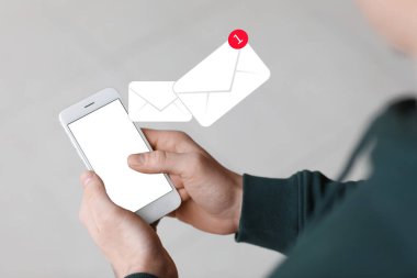 Akıllı telefonlu bir adam e-postalarını kontrol ediyor.