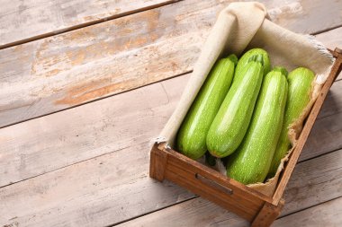 Gri ahşap arka planda yeşil kabaklı bir kutu.