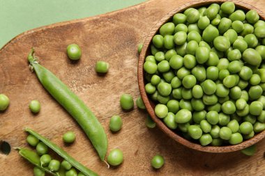 Renkli yeşil bezelyeli kase ve ahşap tahta, yakın plan.