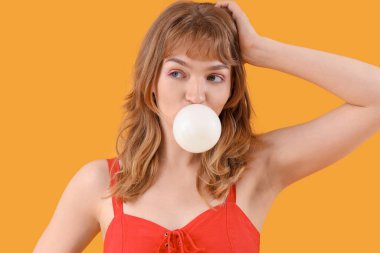 Sarı arka planda sakızı olan genç ve güzel bir kadın. Yakın plan.