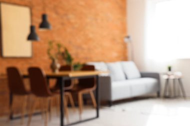 Modern oturma odasının bulanık manzarası rahat gri kanepesi ve kahverengi tuğla duvarın yanındaki yemek masası