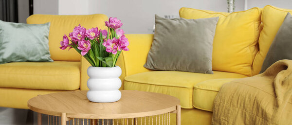 Vase with fresh tulips on table in living room