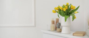 Sarı lale vazosu, mumlar ve şömine rafı üzerine kitap. Tasarım için pankart